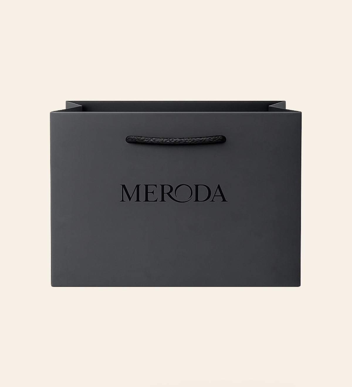 Mattschwarze Geschenktasche mit Kordelgriff und geprägtem Meroda Logo vor cremefarbenem Hintergrund.