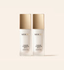 Zwei Meroda Changing Foundation Flakons mit goldenen Kappen nebeneinander auf neutralem Hintergrund.