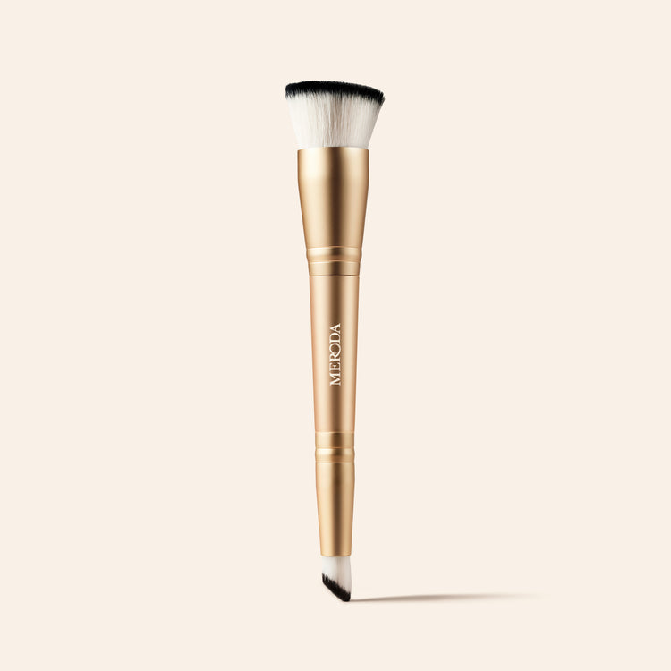 2-in-1 Build & Conceal Brush mit goldenem Griff und zweiseitigen Synthetikborsten auf neutralem Hintergrund.