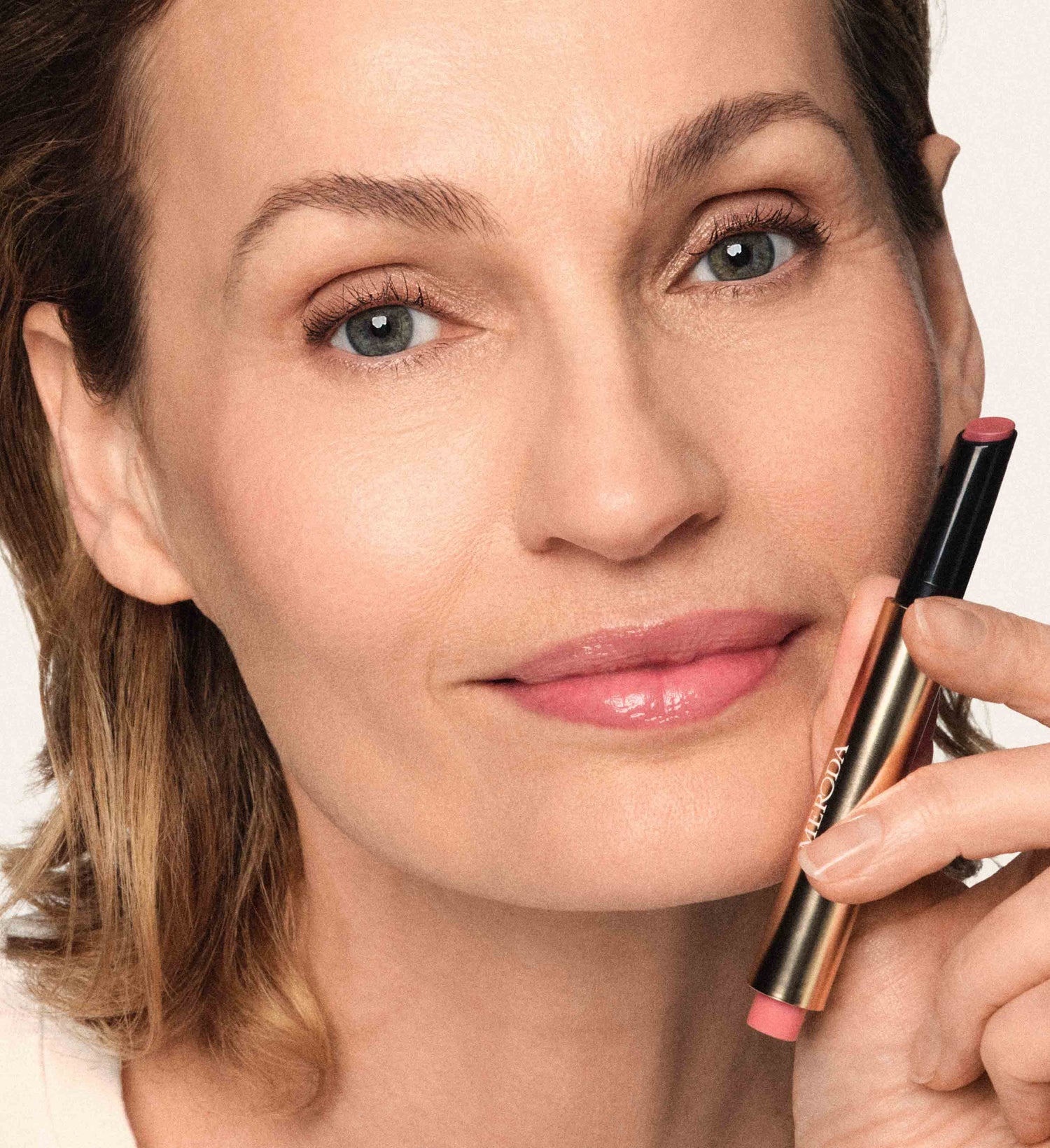 Hydrating Lip Tint in Dusty Rose, gehalten von einem Model für einen natürlichen, gesunden Glow.