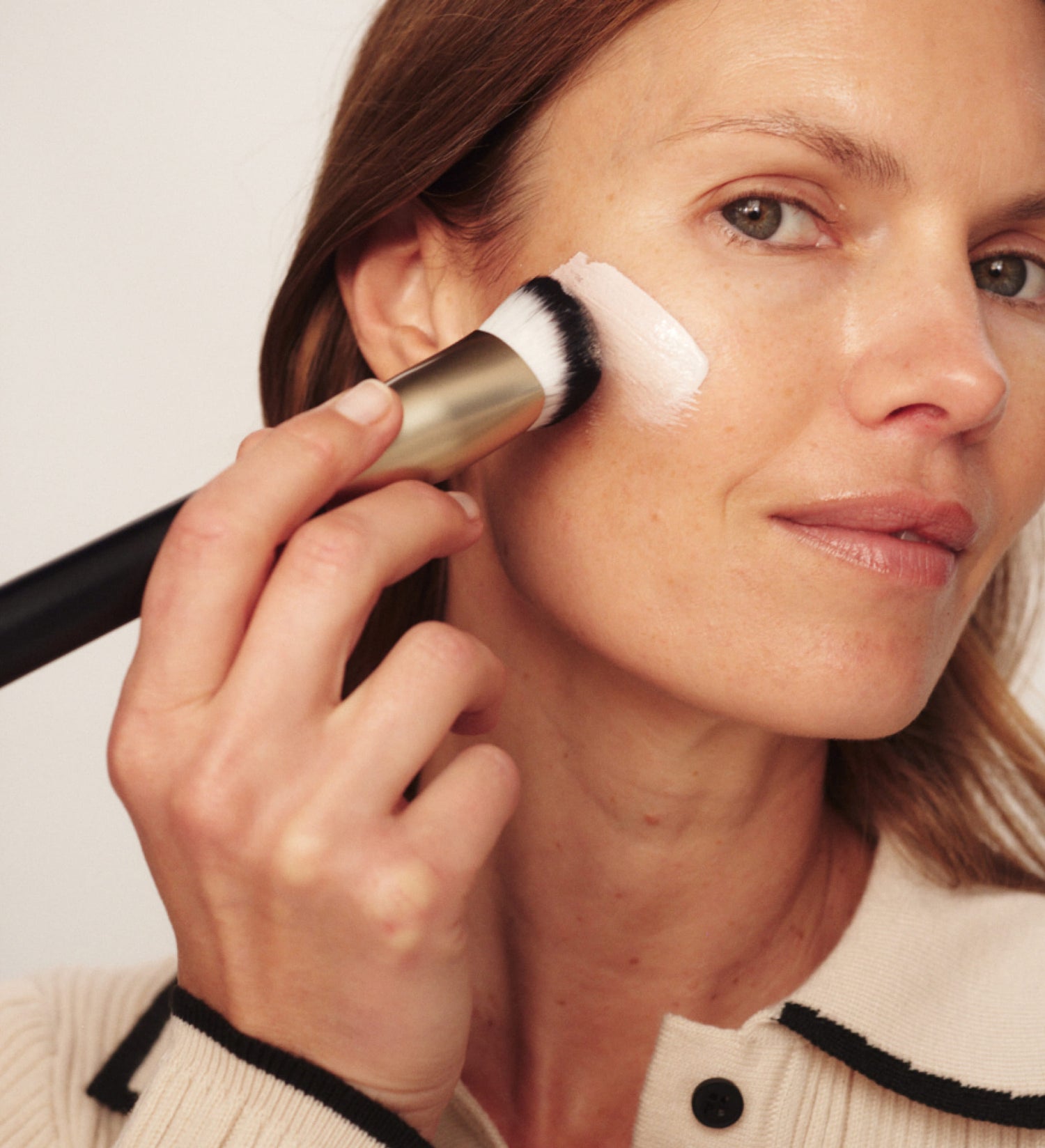 Frau trägt Meroda Cosmetics Changing Foundation mit einem Pinsel für einen natürlichen Look auf