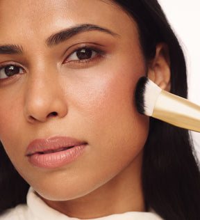 Model verwendet The Essential Brush zum Verblenden von Make-up auf der Wange für ein nahtloses Finish